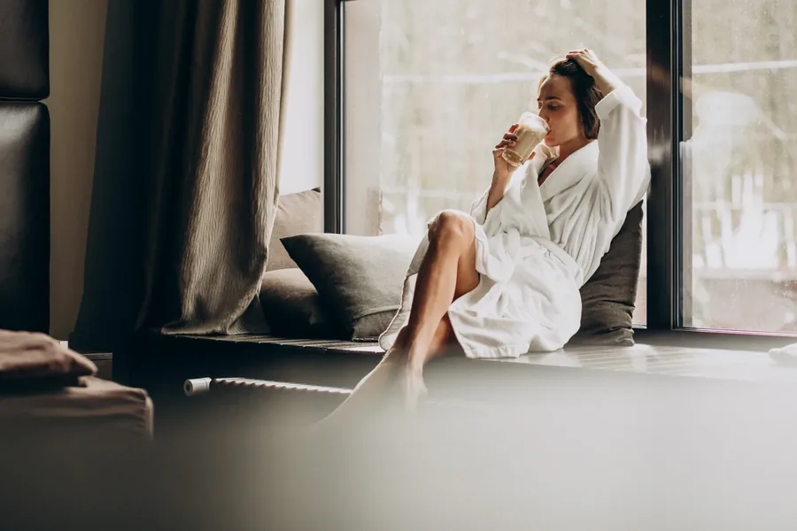 Gast entspannt im Bademantel am Fenster im Hotel Lasalt